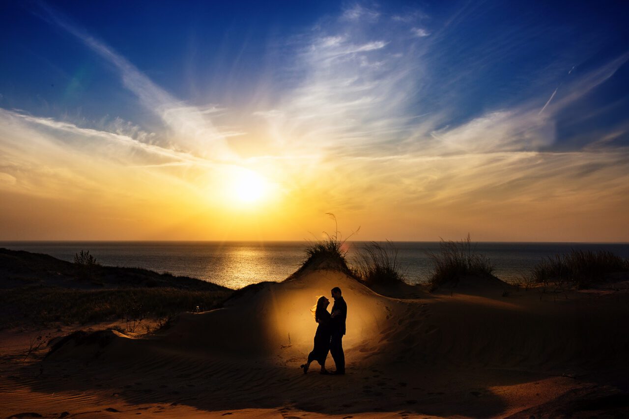 Couple wandering through pierce stocking drive sand dunes at sunset